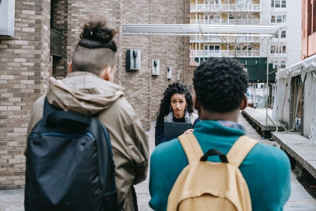 Hispanic student standing behind unrecognizable classmates