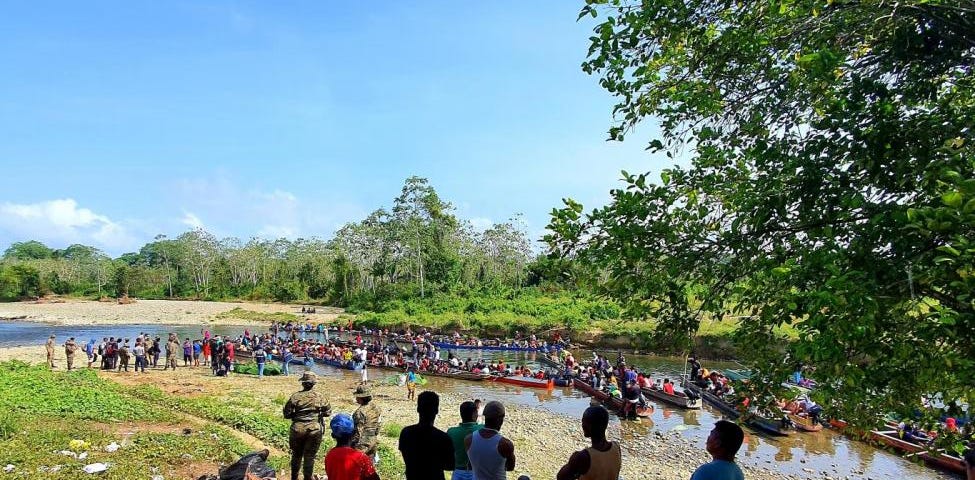 Migrants cross a river