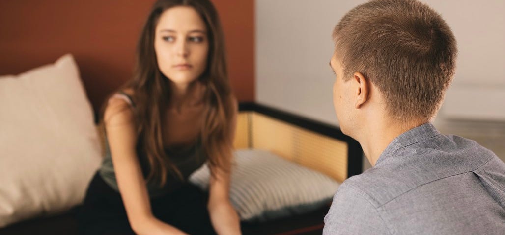 A couple hold hands while having a tense conversation. A one-sided relationship.