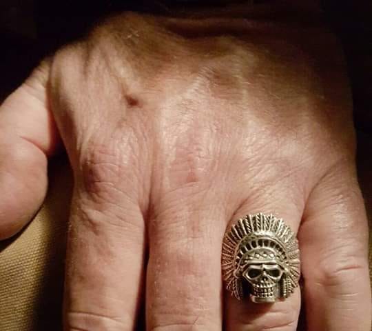 Close up of a man’s hand wearing a Indian war bonnet skull ring.