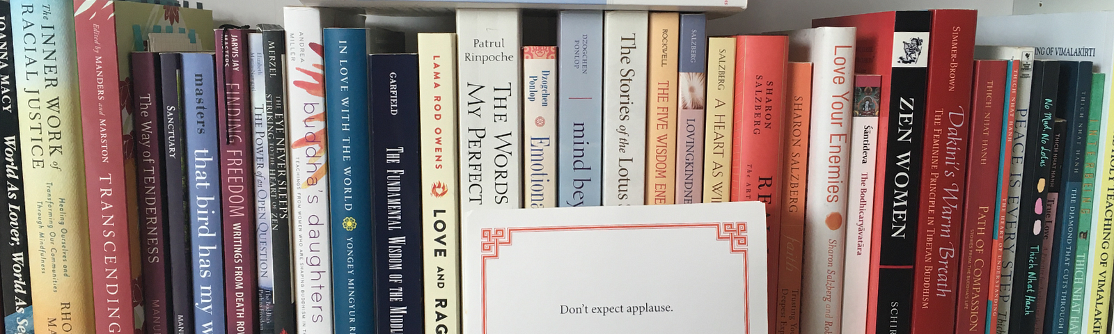 The 59th Lojong slogan card, “Don’t expect applause”, sits on a bookslef surrounded by many Buddhist books, contemporary, classic, and academic.