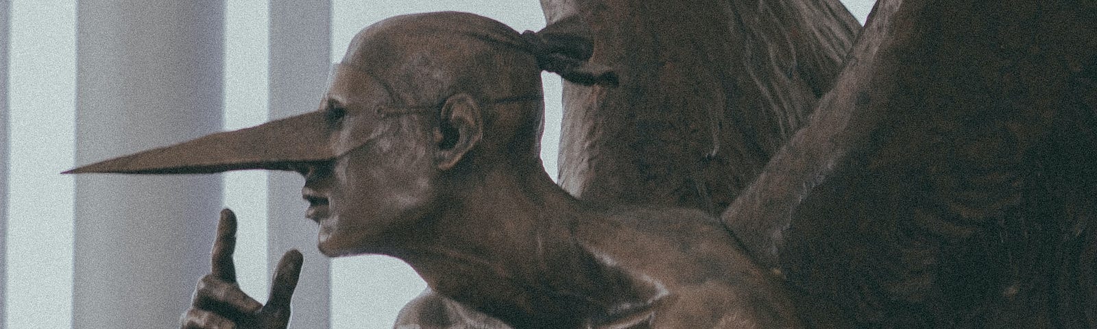 Bronze figure of a gargoyle perched on a globe with a long sharp pointed beak