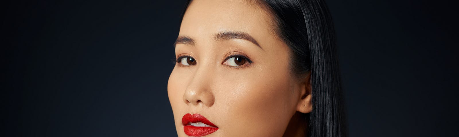 asian-female-model-with-red-make-up-against-black-background— Un Swede