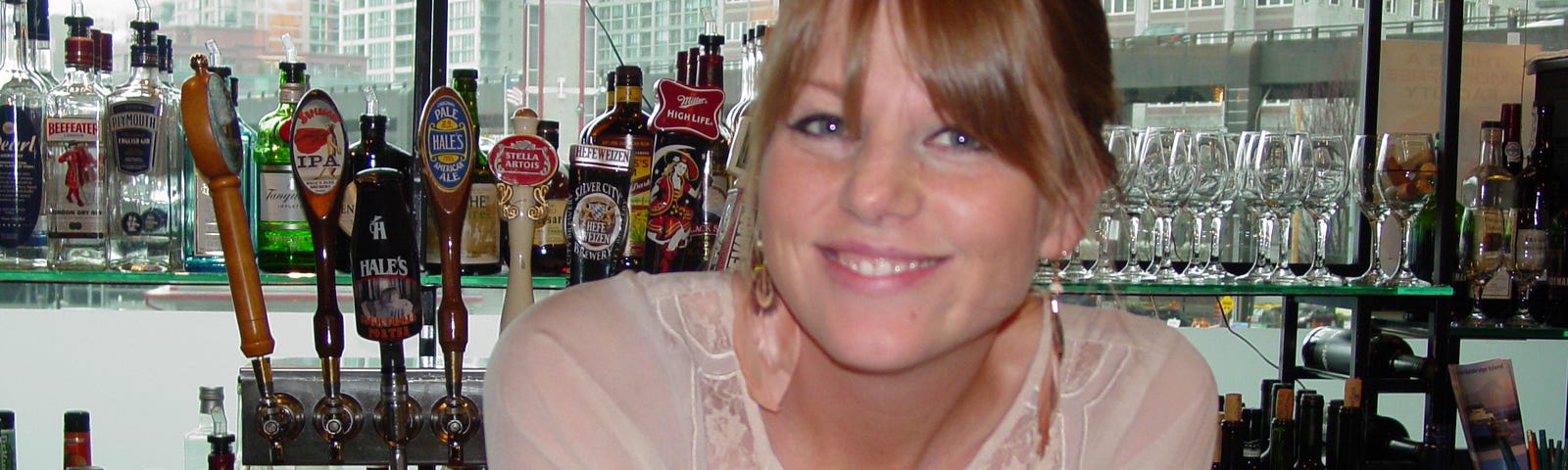 A pretty bartender flashes a sunny smile as she offers a cocktail.