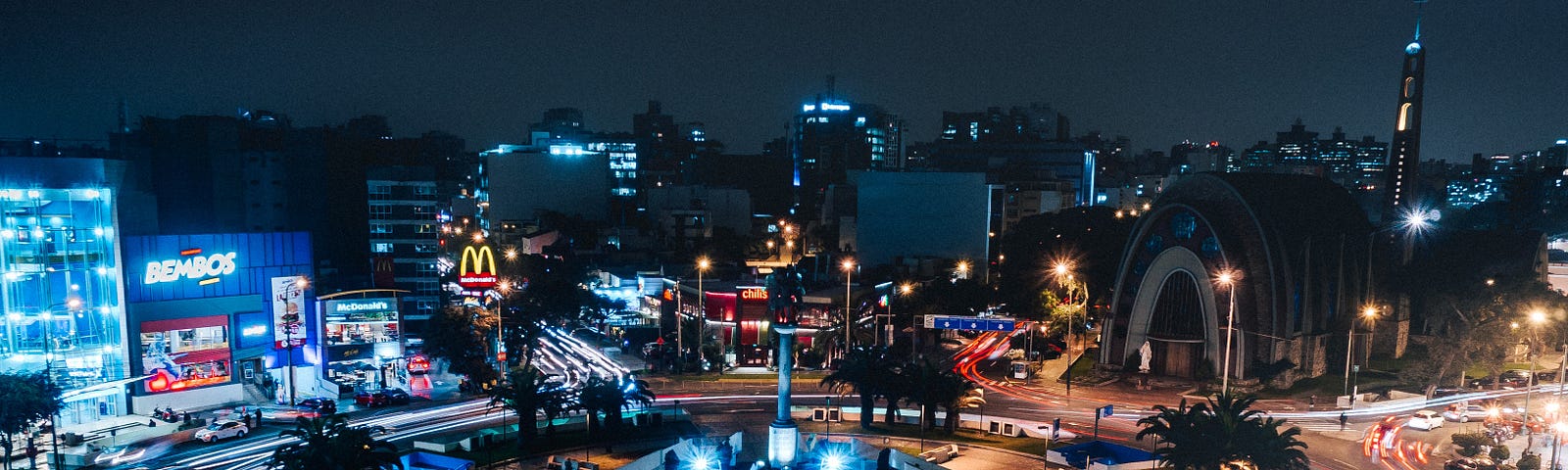 Lima streets at night with a roundabout and urban landscape lit with a long exposure so the lights trail around the roundabout.