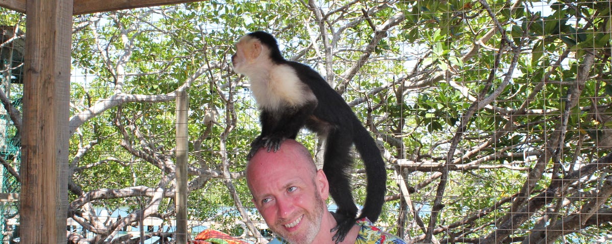 The author in Honduras with a sanctuary monkey climbing up his head.