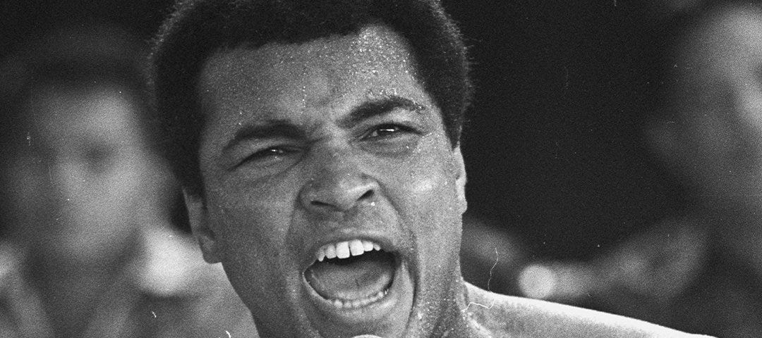 Muhammed Ali shouting into a microphone in his hand