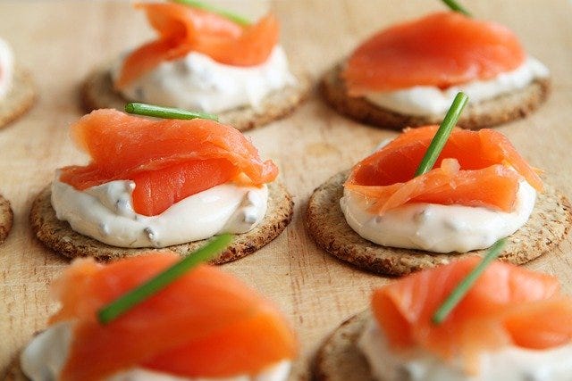 Pieces of fish and cream cheese on top of crackers