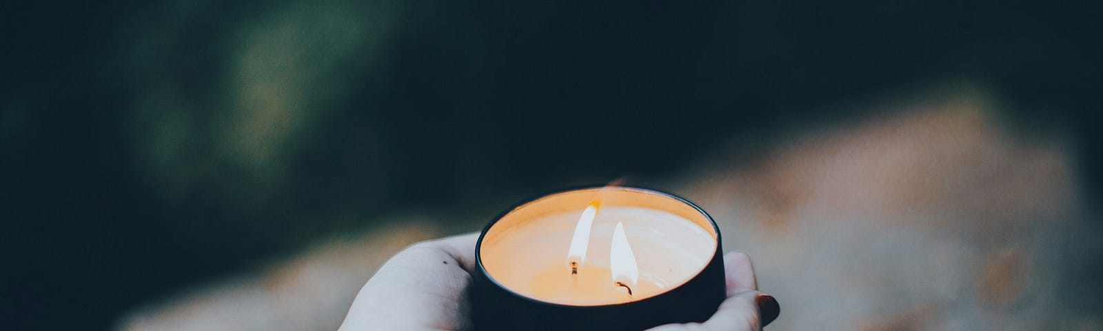 Cupped hands offer a candle with two flames