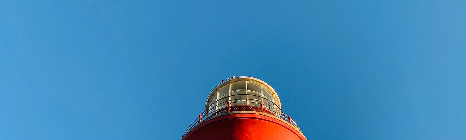 red and white lighthouse set against a clear blue sky