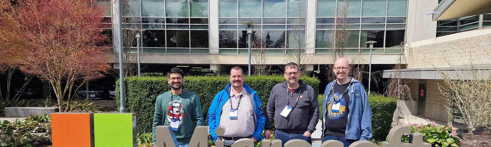 The Microsoft logo sign outside of Microsoft HQ in Seattle with Deepak Agarwal, Mike Hartley, Carl Cookson, Matt Collins-Jones all stood behind it smiling in the sunshine