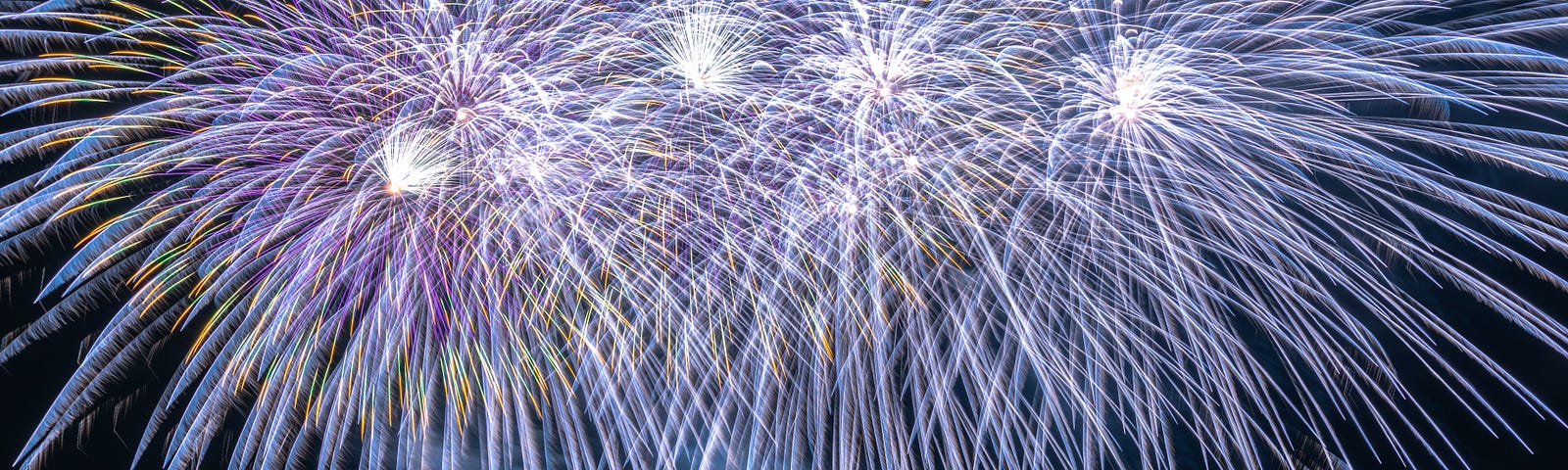 A brilliant blue fireworks display over water.