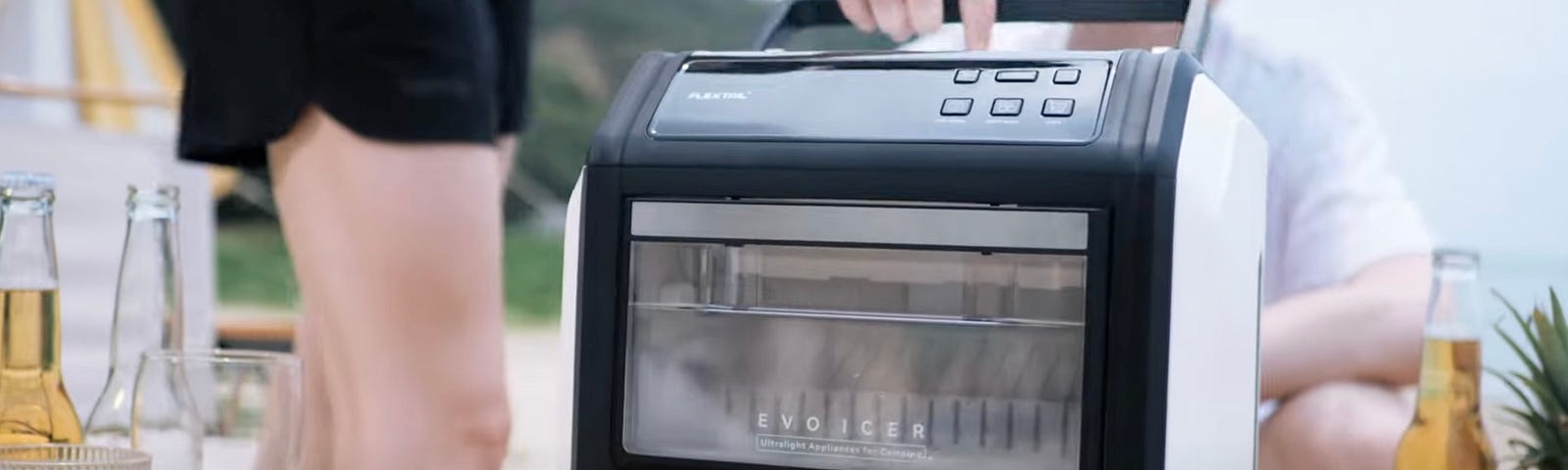 A user picking up her EVO ICER portable ice maker using the handle