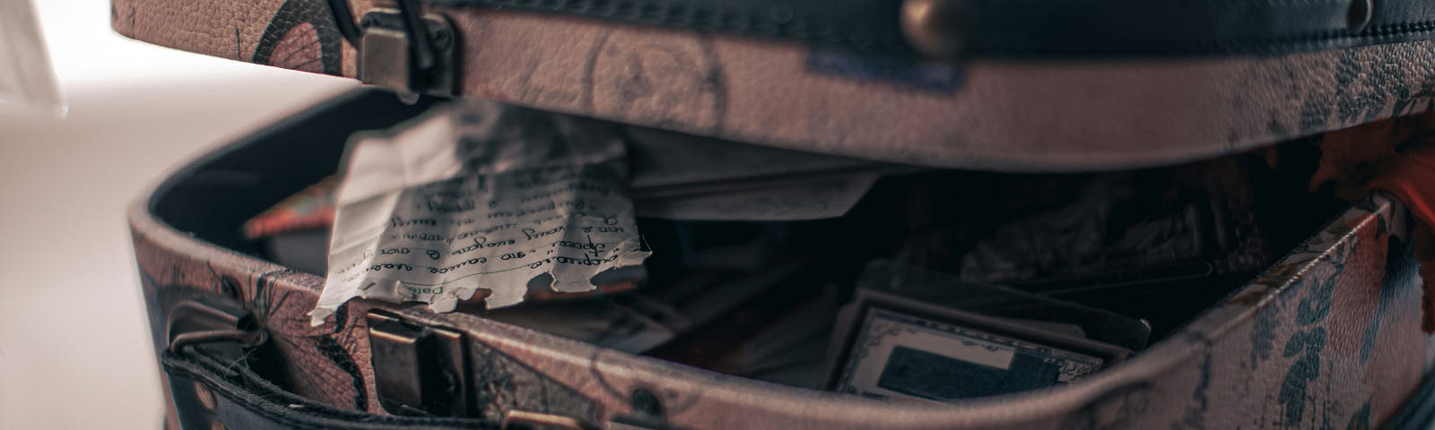 An old suitcase that is open with papers and documents peeking out