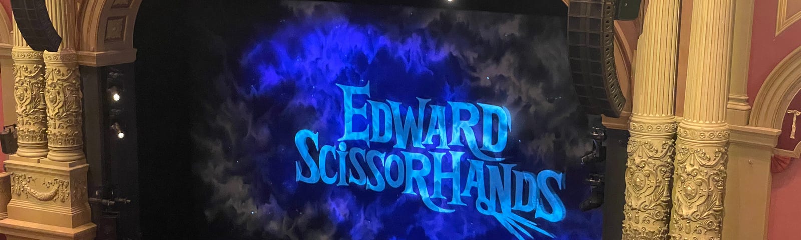 A stage with a screen projecting the words Edward Scissorhands.