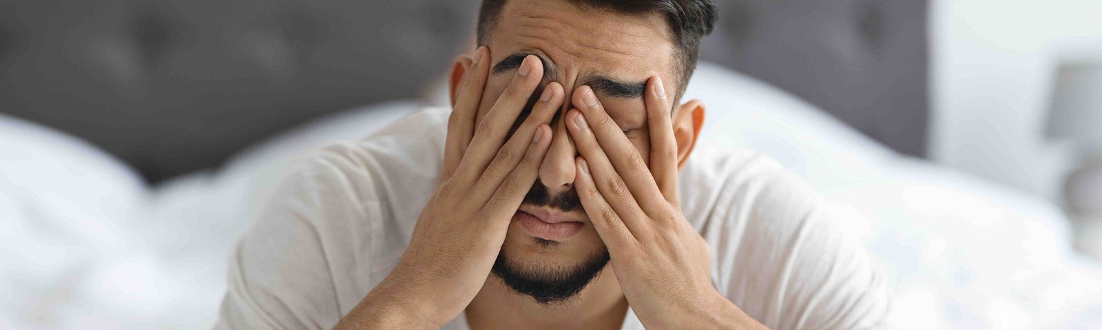 An anxious man holds his head in his hands.