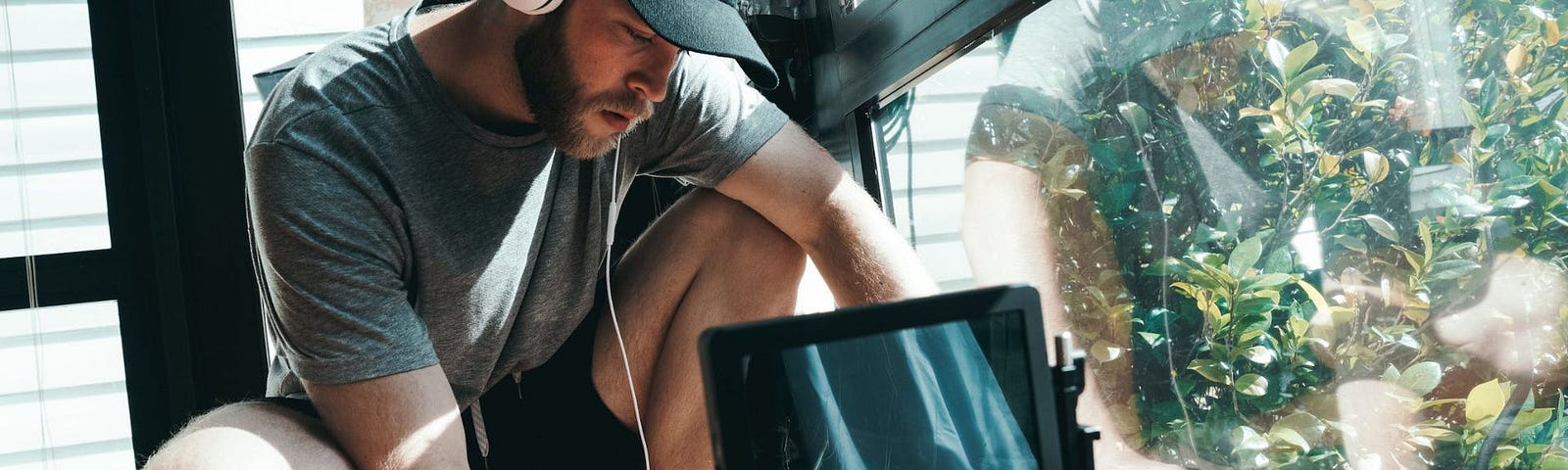 Male filmmaker with headphones on setting up his camera for filming