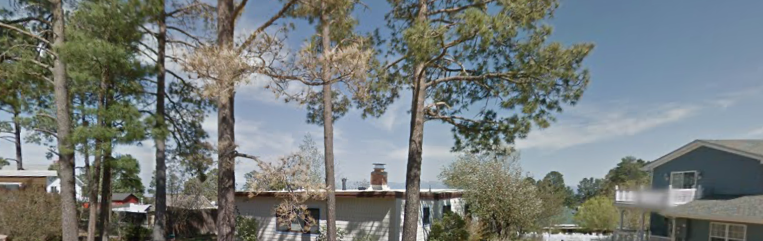 A white single store home with dark blue trim. The house is located in Los Alamos, New Mexico.