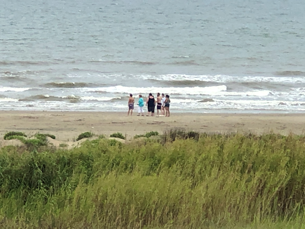 A group of people at the beach, watching the waves roll in