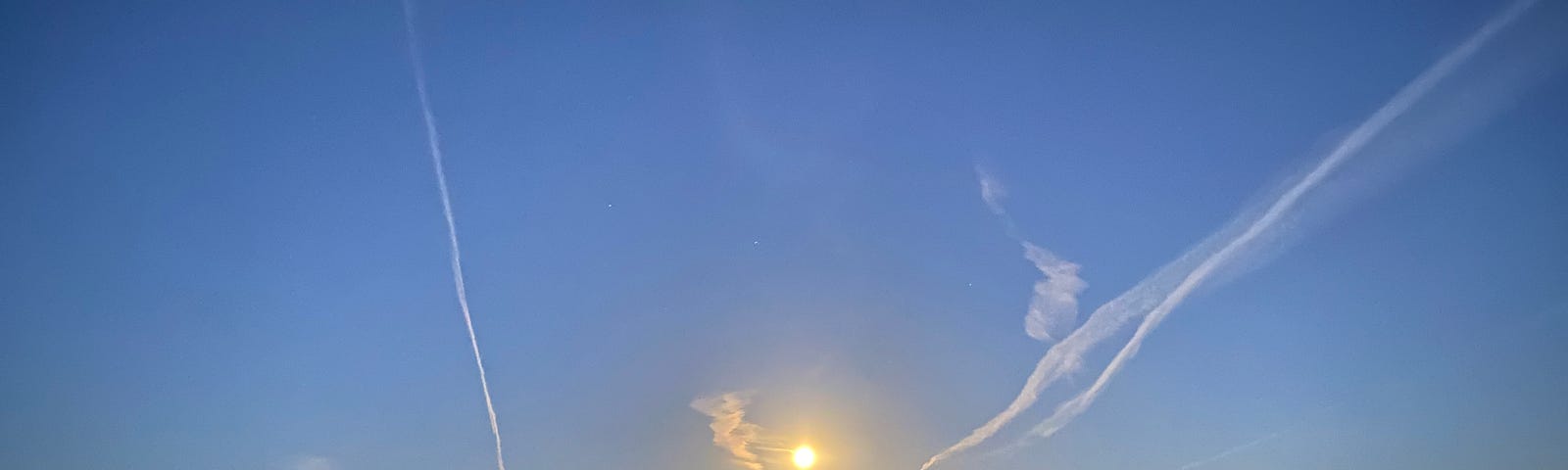 Bright moon to the west illuminated by the rising sun to the east.