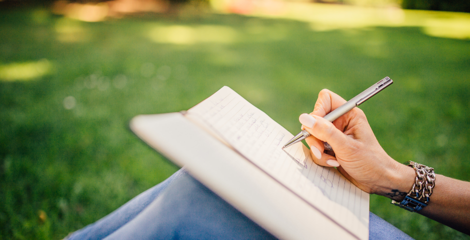 Young lady handwriting in a journal sitting in the yard