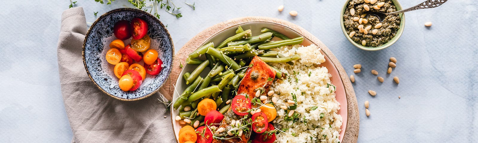A bowl of green beans, tomatoes, and rice, on a wooden board.