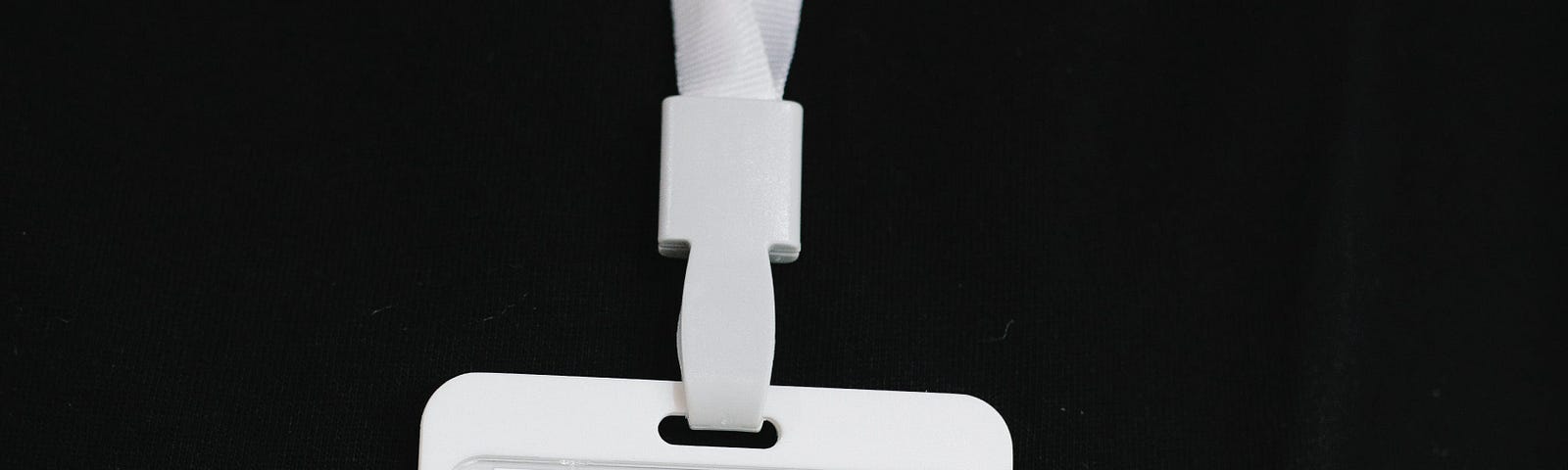 blank white name tag on lanyard against black background