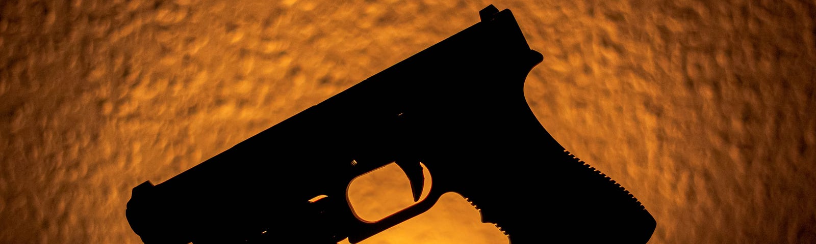The silhouette of a handgun against an orange background.