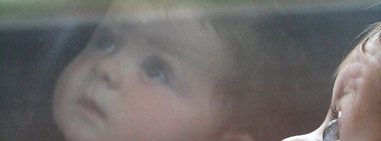 A baby reflected in the window of a fast moving train.