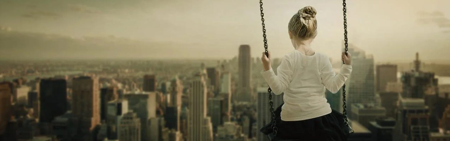 A young girl swinging above the world, she wears a black skirt, white long sleeve jumper, gumboots on her feet and her blonde hair held up in a scrunchy.