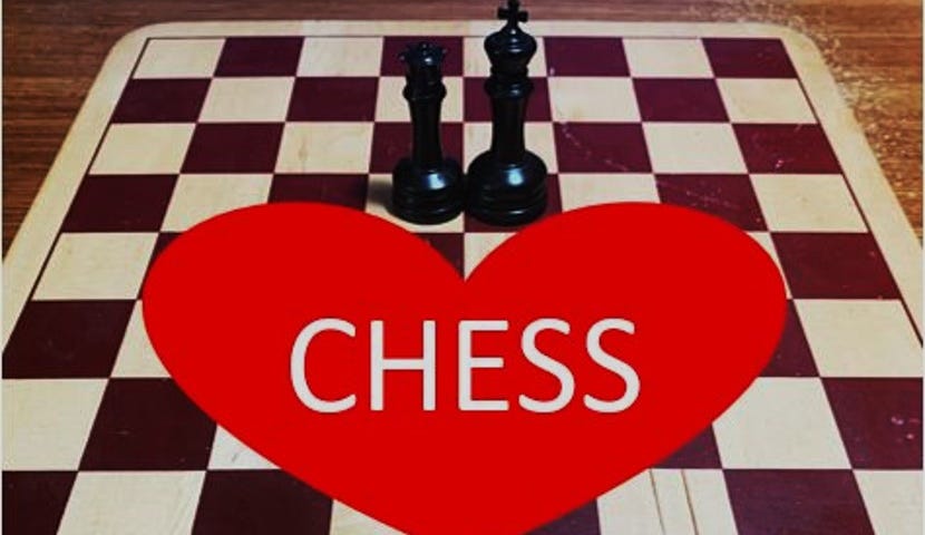 Black king and queen in center of author’s well-used wooden chess board. Red heart in center with the word CHESS.