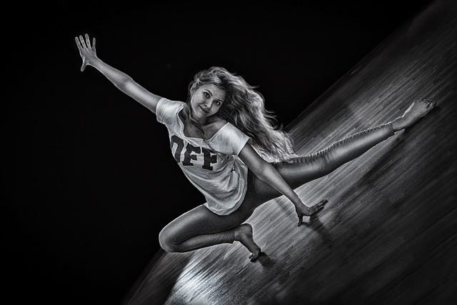 Young woman, dancer, long hair, wears leggings and an oversized T-shirt with Large logo, monochrome image, She strikes a crouched pose with one arm and one leg extended