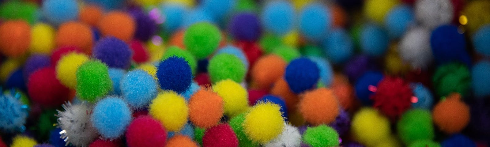 Color photo of a bunch of colorful pom poms.