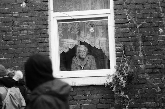 Black and white photo of elderly woman looking out of the window