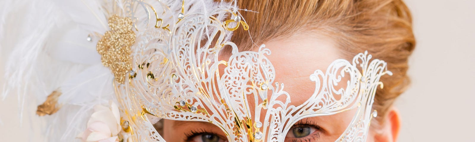 A lady wearing a gown with a white masquerade mask in front of her eyes.