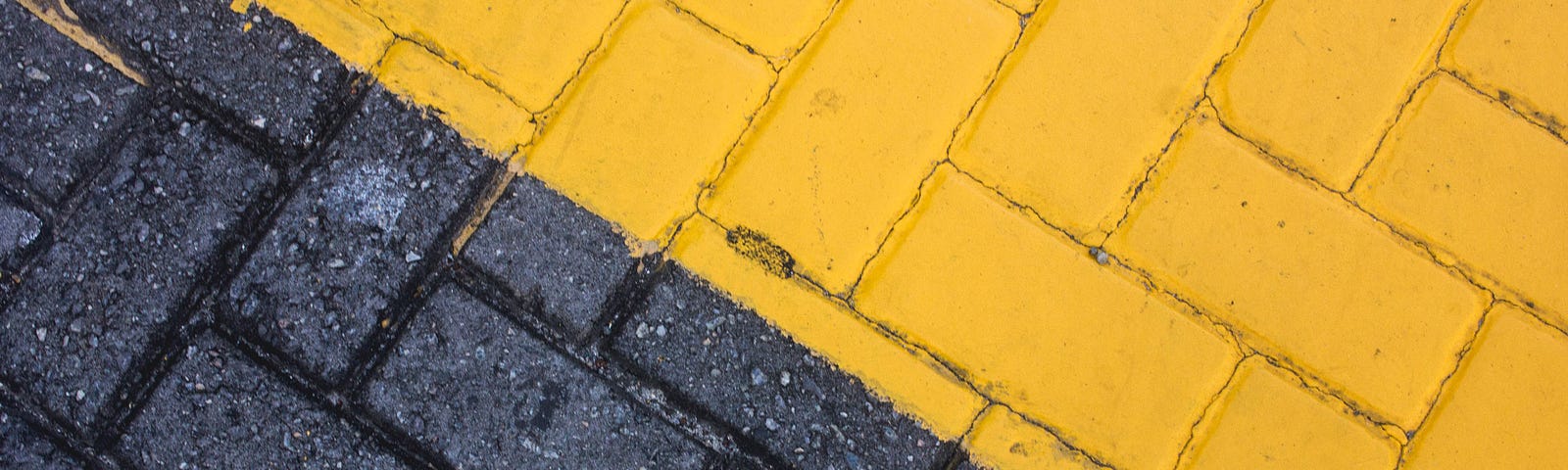 Brick road, half unpainted, half painted yellow in a diagonal composition.