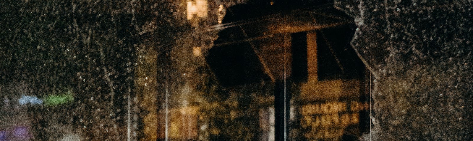 Broken windowpane in foreground, with a dark cityscape behind it