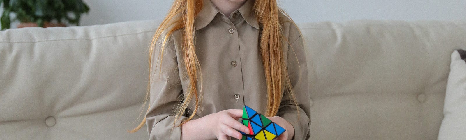 A child holding a pyramid Rubik’s Cube