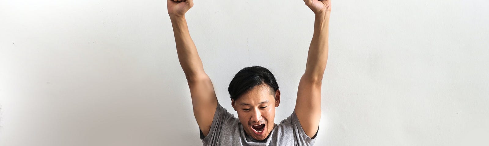 Man looking at laptop with hands raised