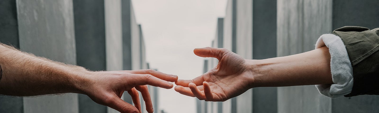 Hands reaching out to touch between two walls.