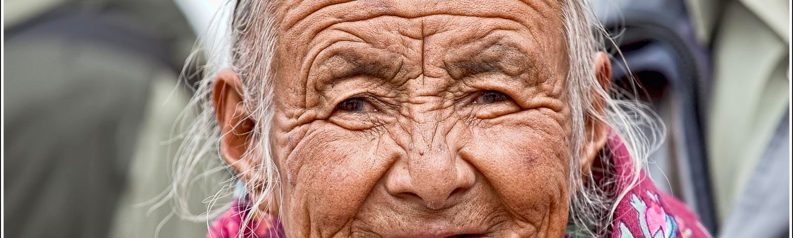 Old Tibetan woman with many wrinkles and a smile that stands above the suffering. Suffer consciously is the end of suffering.