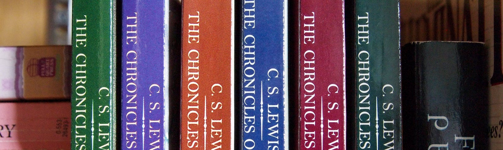 Six copies of The Chronicals of Narnia, by C.S Lewis displayed to show their spines of various colours.