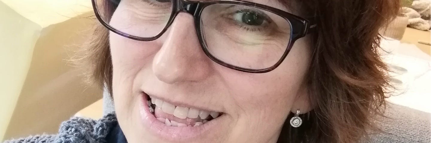 A picture of the writer AnnaBannana, dark haired, wears glasses, loves a cardigan