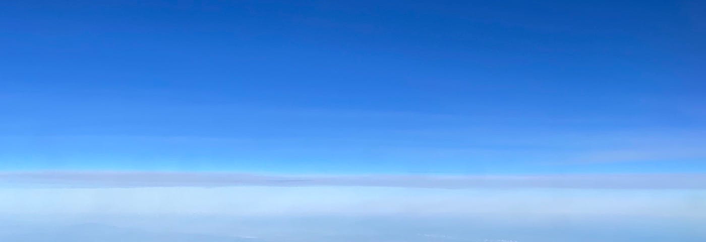 Blue sky above the cloud line with the earth far below.