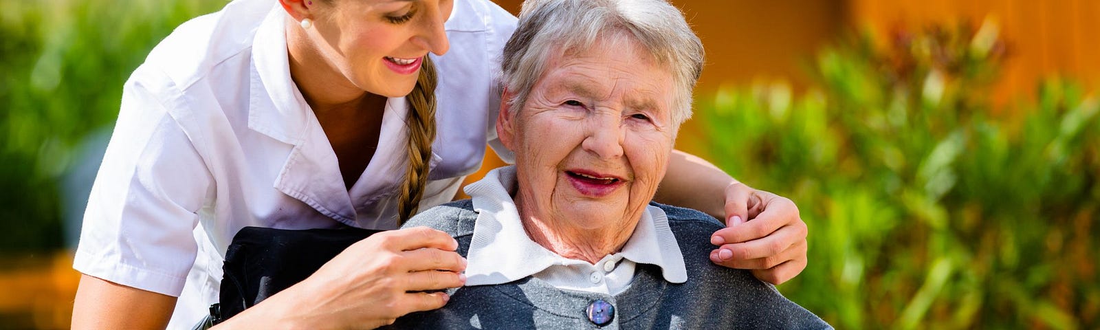 A woman in a wheelchair gets a hug from a nurse in a white uniform