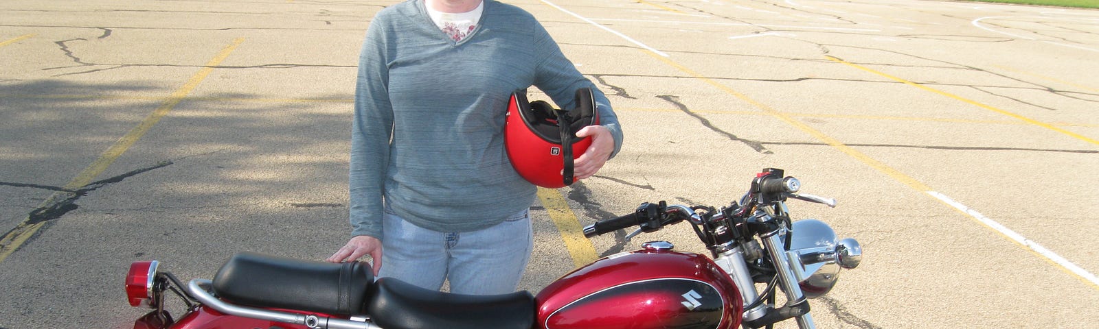 This shows a woman standing behind a red motorcycle.