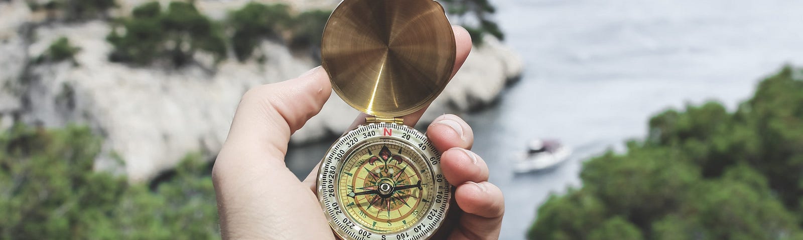 Person holding compass with sea view in the background