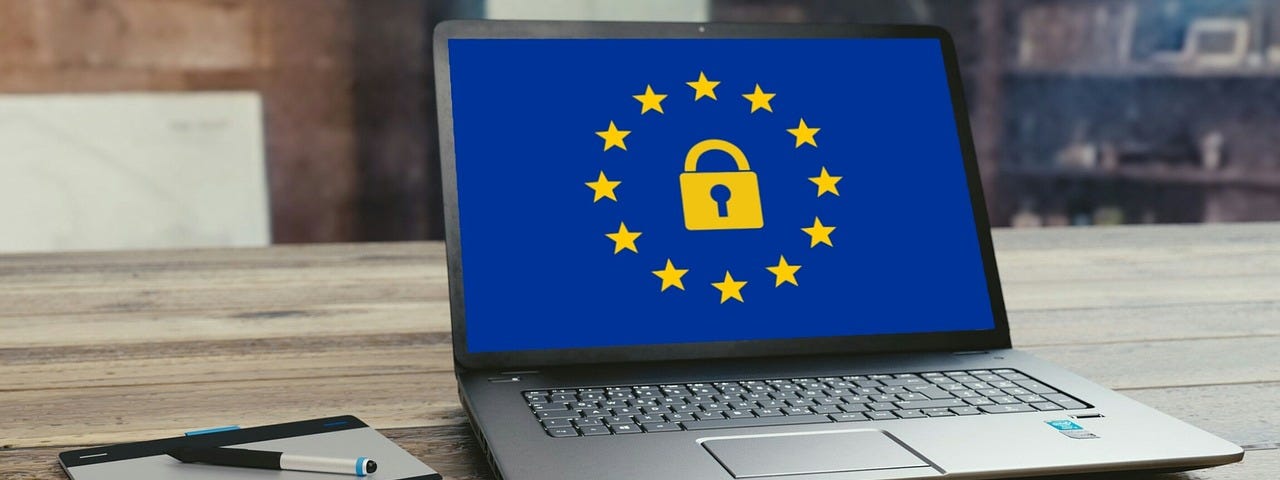IMAGE: An open laptop on a table and with a blue screen with a lock surrounded by the EU stars in yellow