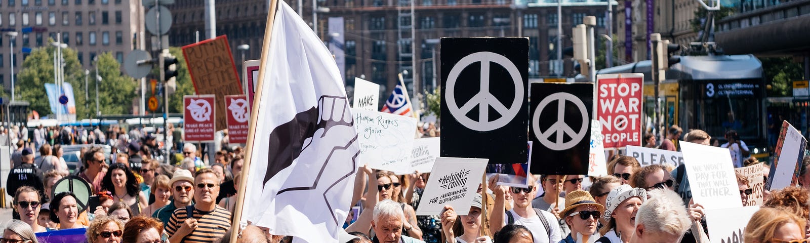 A crowd of people march holding placards with peace symbols and other banners to demand respect for human rights and democracy in Helsinki.