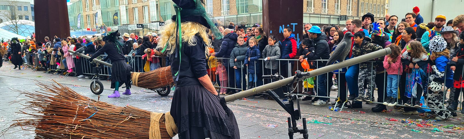 Witch on a broomstick bike during carnival parade.